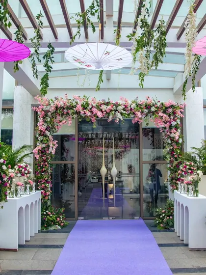 The main doorway for the engagement party, framed by a beautiful arch of pink and white flowers, leading guests from the outdoor pergola to the indoor celebration.