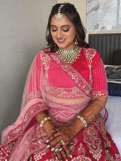 For this bride, we chose golden shimmery eyes and a warm-toned lip to complement her pink and red bridal lehenga. It's a classic look with a touch of modern glam.
