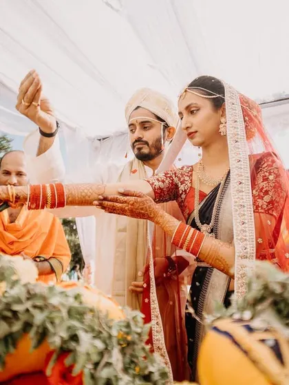The couple performs a wedding ritual together, their hands joined in a moment of unity.