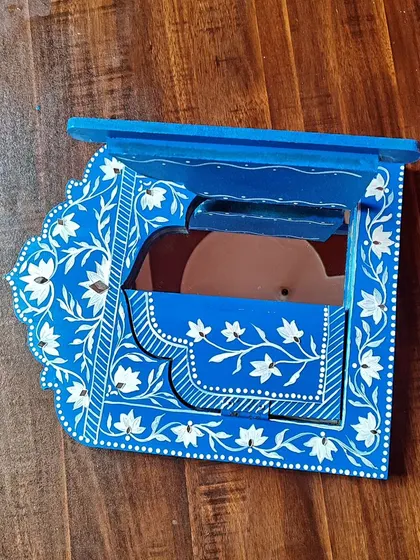 A single Jharokha frame, showing the detail of the hand-painted white flowers on the blue wood.