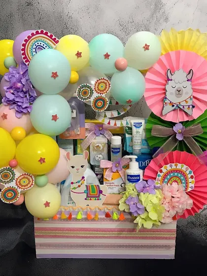 A closer look at our 'No Drama Llama' themed gift hamper, filled with baby care essentials from Mustela. The colorful paper fans and llama cutouts make it extra cheerful.