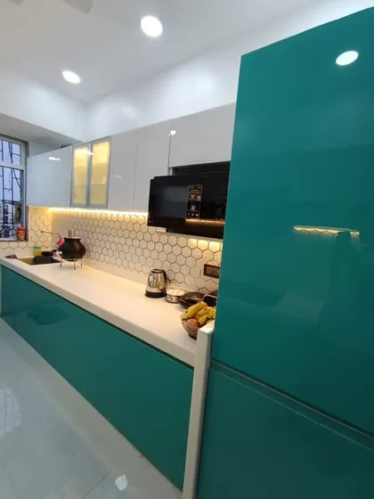 The high-gloss laminate finish on these teal cabinets is not only stylish but also easy to clean and maintain, making it a practical choice for a modern kitchen.