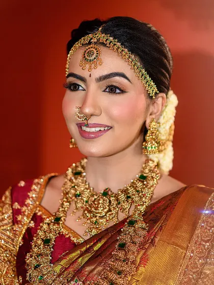 A radiant bridal smile that lights up the frame. This close-up captures the happiness of the moment, along with the flawless makeup and stunning gold jewellery.