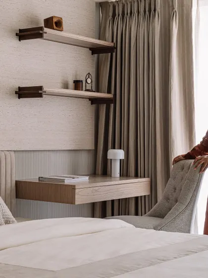 The father's bedroom features a floating desk and custom shelving, creating a functional workspace within the serene sleeping quarters.