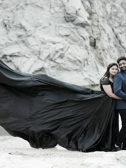 A dramatic pre-wedding photo by a quarry lake, with the bride's long black gown flowing in the wind, creating a powerful and moody image.
