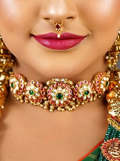 A close-up on the bride's smile and jewellery. This shot highlights the beautiful temple-style choker and the perfectly applied lipstick.