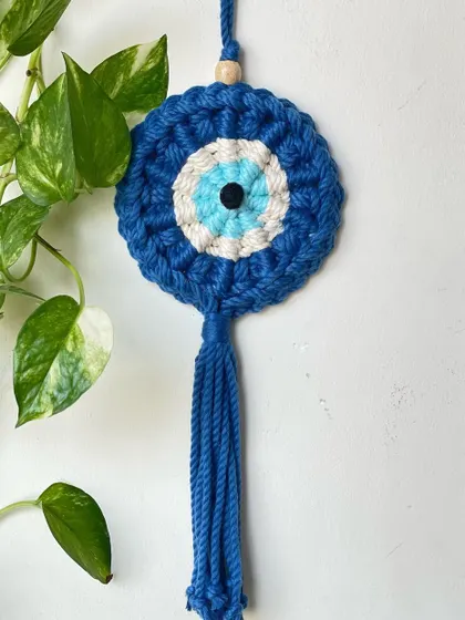 This Evil Eye hanging looks beautiful against a backdrop of green leaves. It's a perfect charm to hang near a window or in your entryway.