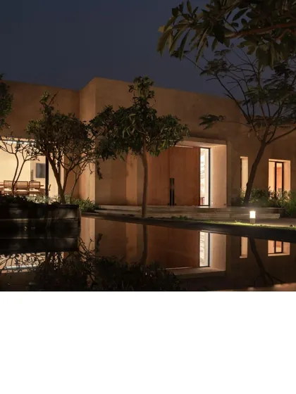 Earthsong at night, where strategic lighting highlights its clean, monolithic form. The warm glow from the interiors creates a welcoming beacon in the tranquil landscape, reflecting beautifully in the water.