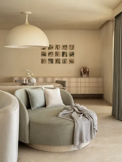 A closer look at the swiveling love seat in a soft green, a perfect cozy corner in the Soft Serve living room. The space is all about comfort and calm, modern design.