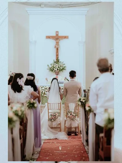 A view from the back of the church aisle as the couple stands before the altar. This perspective captures the solemnity of the ceremony and the support of their loved ones.