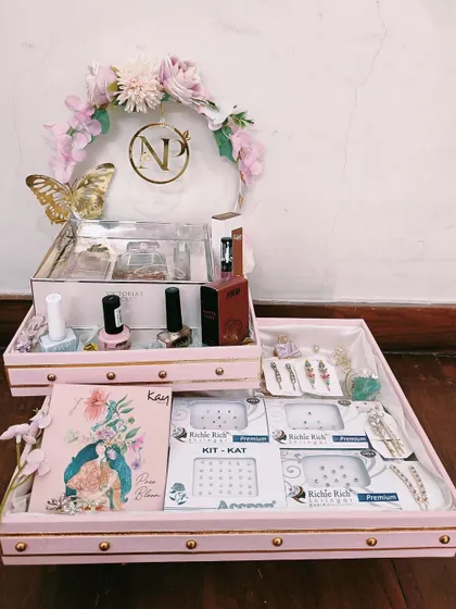 A personalized trousseau tray for a bride's beauty essentials. This pastel pink set includes a monogrammed vanity box for makeup and a separate tray for accessories, all tied together with a floral and butterfly motif.
