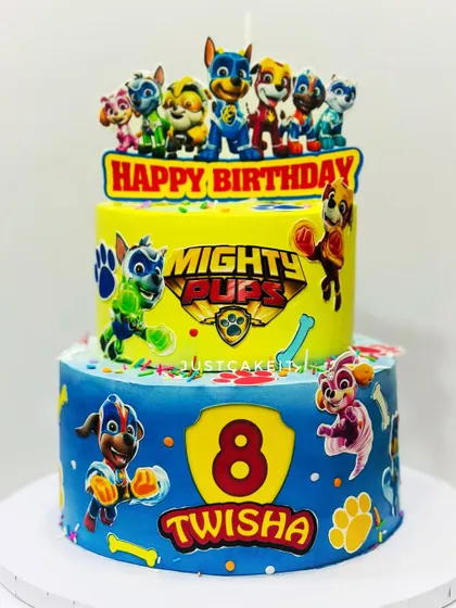 A vibrant two-tier Mighty Pups theme cake. The bright yellow and blue colors and action-packed characters make this a very dynamic design.