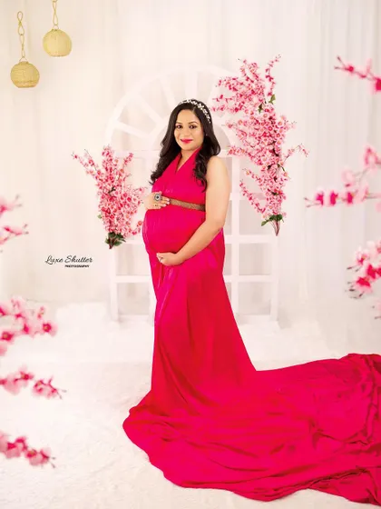 A vision in pink. This vibrant satin gown looks stunning against the bright, floral-adorned backdrop, creating a cheerful and feminine portrait.