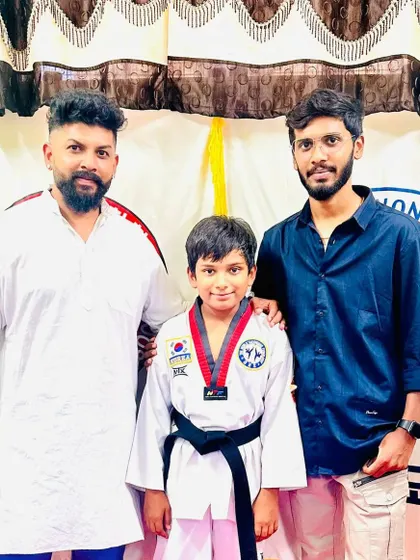 A young student celebrates earning his black belt.