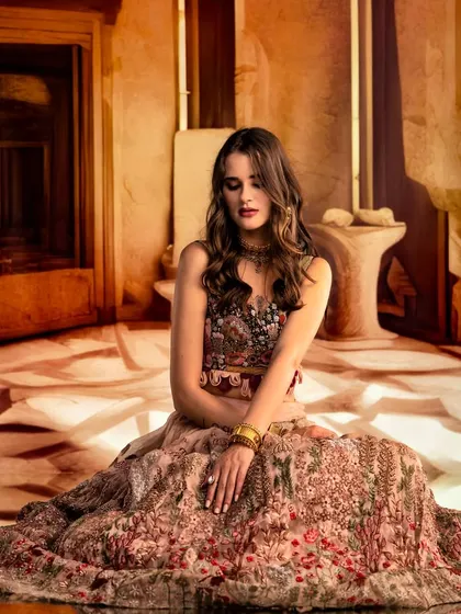 An abstract, sandy-toned environment is projected to create a minimalist yet intriguing setting. The focus is on the model's pose and the beautiful floral patterns of her dress.