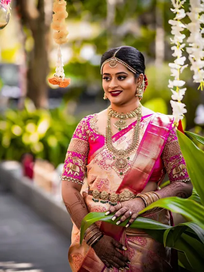 A bride in a peach and pink Kanchipuram saree with a blouse featuring elephant motifs on the sleeves, a popular traditional design.