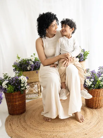 A quiet moment of connection between mother and son. The soft, neutral outfits and floral background create a serene atmosphere.