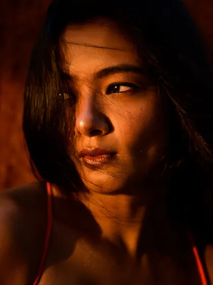 A soft and intimate close-up, with the wind gently blowing the model's hair across her face.