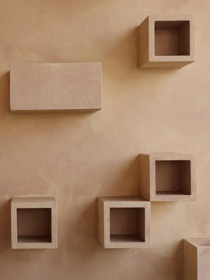 Detail of the textured wall and sculptural cube shelves from our urban balcony project. The earthy finish of the wall and the simple geometry of the niches create a tactile and visually interesting surface.