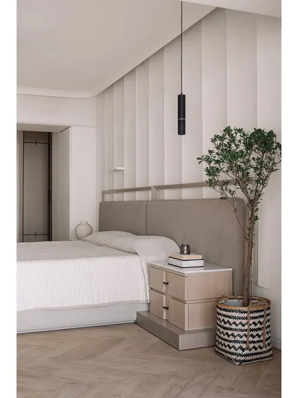 A full view of the master bedroom, showing the striped wallpaper that adds subtle pattern and the minimalist pendant light.