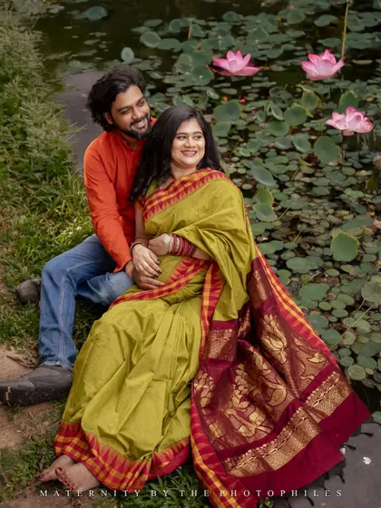 This shot showcases the full splendor of the Kanchipuram saree against the soft greens and pinks of the lotus pond. It’s a perfect example of how I blend traditional attire with natural outdoor settings for maternity shoots.