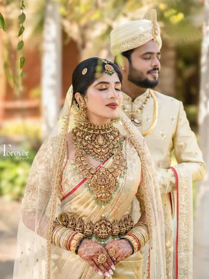 A sun-kissed portrait of a bride in her golden wedding saree. The light enhances her glowing skin and the rich details of her antique-finish jewellery.