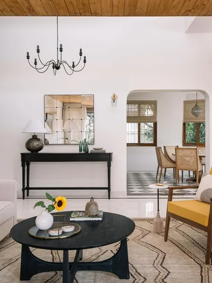 A living room from 2023 that mixes modern and traditional elements, with a pop of yellow in the armchair.