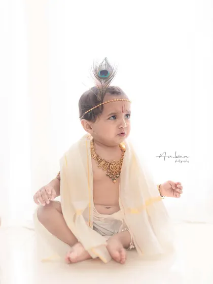 A contemplative moment. The simple styling and clean background allow the baby's sweet expression and posture to be the main focus of the photograph.