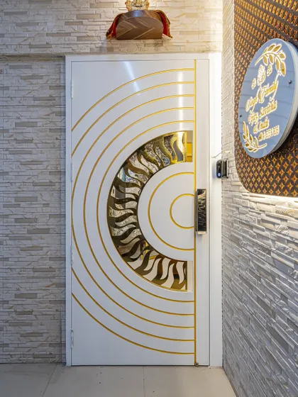 Your main door is the first thing people see. I designed this custom safety door with a white Duco paint finish and a PVD coated jaali, matching the inner door's pattern to create a grand and cohesive entrance.
