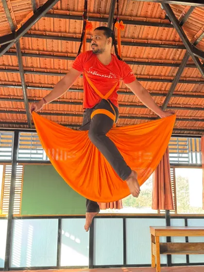 Floating effortlessly in the orange hammock, this student showcases the playful and liberating side of aerial yoga.