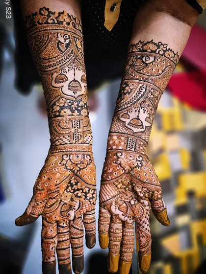 A beautiful bridal mehendi with prominent peacock and jhumka motifs. The use of shading and negative space makes the central elements stand out.