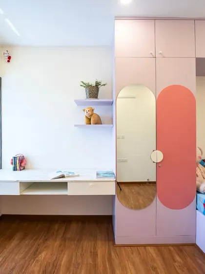 A smart and space-saving design for a shared kids' room, with a built-in bed, wardrobe, and a long study desk by the window. The pink and lavender colors give it a soft, playful feel.