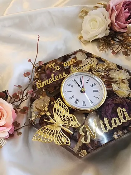 This hexagonal table clock is a perfect example of a personalized gift. It features preserved flowers, the recipient's name, a custom message, and a delicate golden butterfly accent.
