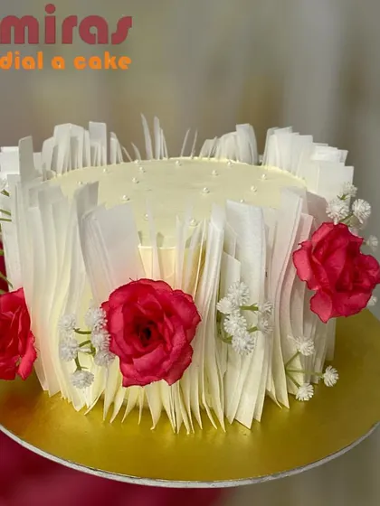 An artistic and modern cake decorated with abstract white chocolate sails and fresh red roses. This design is perfect for a sophisticated and contemporary celebration.