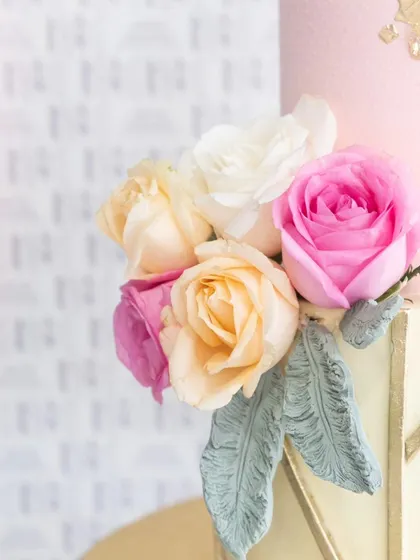 A detailed view of the fresh roses and textured leaves on this elegant floral cake.