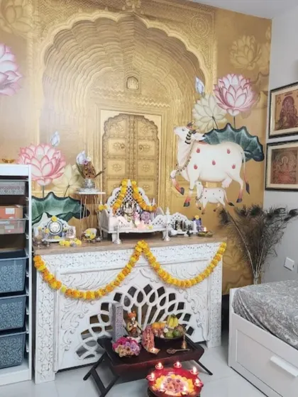 A beautiful pooja space created with a golden-hued Pichwai wallpaper featuring the sacred cow, perfectly complementing the home temple setup.