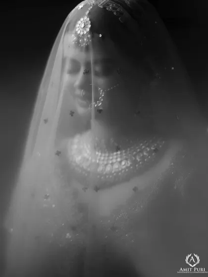 An artistic black and white portrait of the bride under her veil. The soft focus and monochrome tones create a dreamy, timeless, and emotional image, full of quiet anticipation.