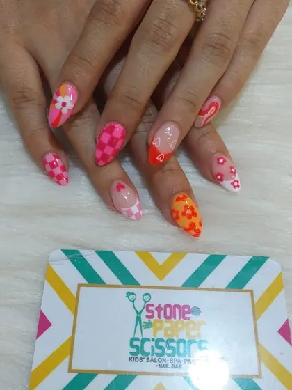 A playful and colorful set that combines multiple trends. I used a pink checkerboard pattern, floral details, and heart cutouts for a fun, mismatched look on stiletto nails.