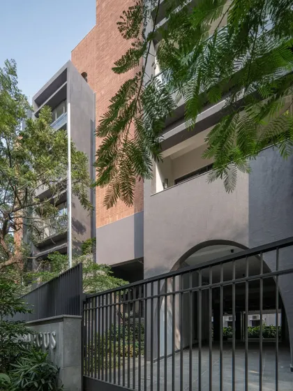 Close-up details of the ARCUS facade, highlighting the texture of the brickwork, the depth of the balconies, and how the structure was designed to accommodate existing trees.