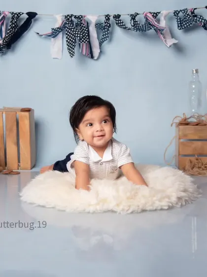 This adorable six-month-old is enjoying tummy time on a fluffy rug during his milestone photoshoot.
