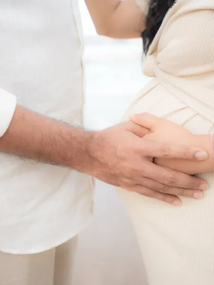 Sometimes the simplest gestures tell the biggest story. This close-up shot focuses on the couple's hands gently cradling the baby bump, a powerful and intimate detail from their outdoor pregnancy photoshoot.
