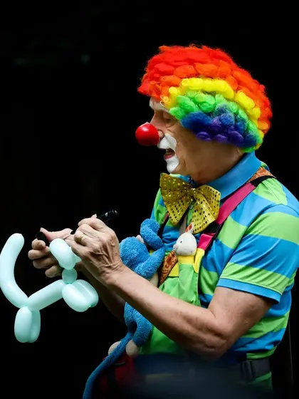 A clown providing entertainment with balloon twisting, a must-have for a true carnival atmosphere.