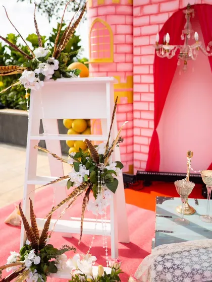Even simple props can be elegant. Here, a white ladder is adorned with feathers and floral arrangements, serving as a unique decorative piece for a princess-themed event.