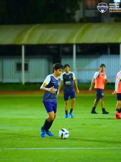 A player dribbles with his head up, scanning the field for passing options during a training session.