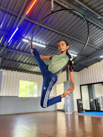 Striking a powerful pose. This student shows off a dynamic leg extension on the aerial hoop, a move that requires both strength and balance.
