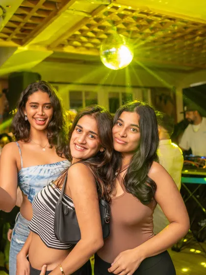 A snapshot of the party under the disco ball. The yellow lighting and happy faces capture the warm, nostalgic vibe of the night.