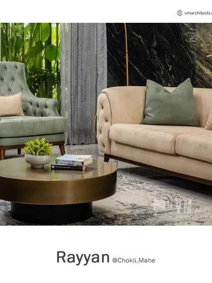 A close-up of the seating in the Rayyan living hall, showing the contrast between the soft green tufted armchair and the beige sofa against the dark marble wall.
