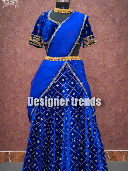 A royal blue velvet half saree with diamond-patterned embroidery on the skirt, available for rent.