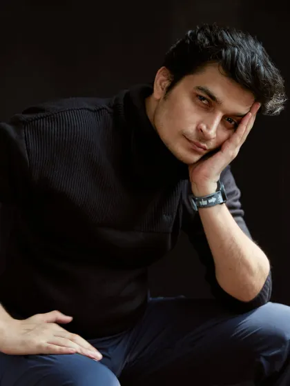 A classic, moody actor headshot. The dark turtleneck and background draw all the attention to the face, while the soft lighting creates a sense of depth and introspection.