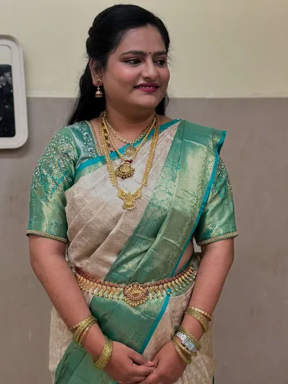 Rakshitha's reception look. The off white and teal green saree is draped elegantly, allowing the heavy temple jewelry to be the star of the show. The drape is comfortable for a long evening of celebrations.